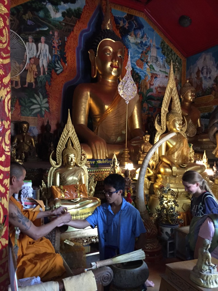 Harry receives a bracelet representing luck and merit from a senior monk at Wat Doi Suthep. 