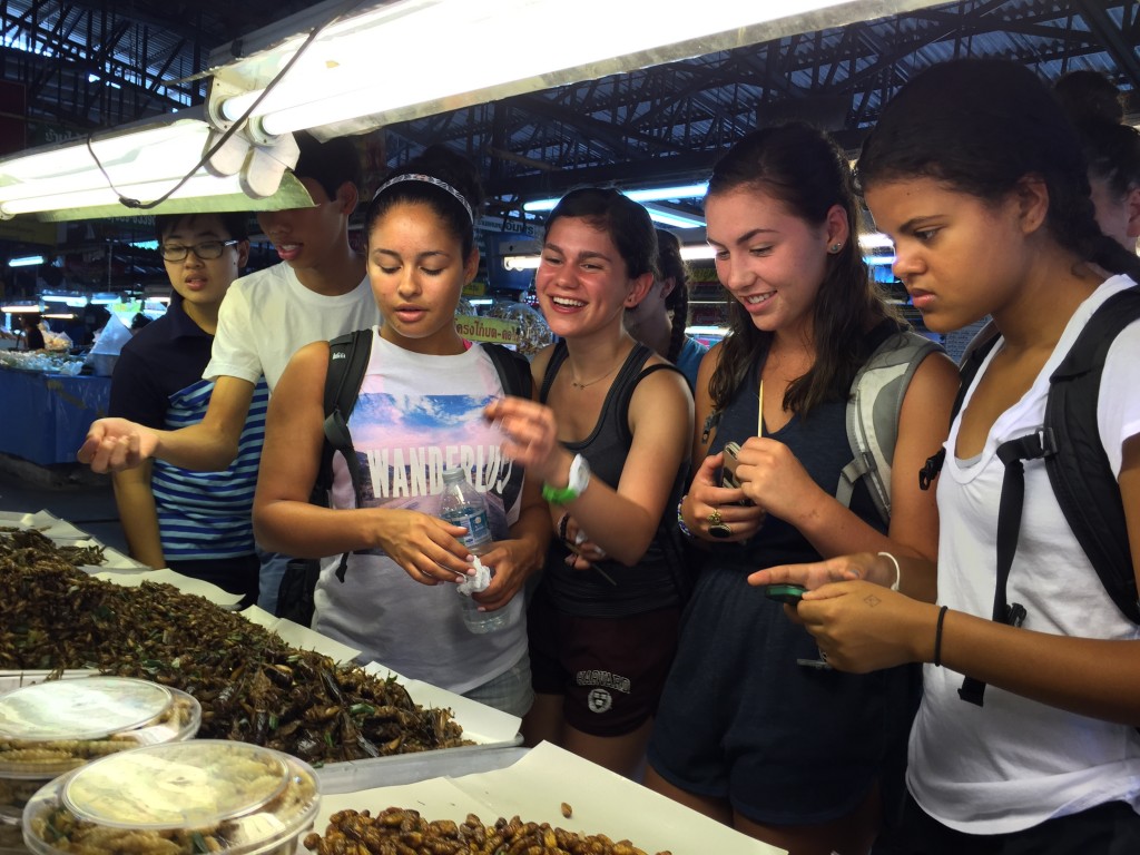 Students sample crickets, grasshoppers, silk worms and bamboo worms deep fried in soy sauce at the local market.
